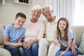 Portrait Of Grandchildren Sitting On Sofa With Grandparents