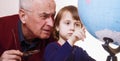 Portrait of grandfather and granddaughter looking at globe and planning travel Royalty Free Stock Photo