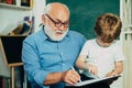 Portrait of grandfather and grandson on blackboard in classroom. Father and son - generation people concept. Kid with Royalty Free Stock Photo