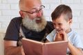 Portrait of grandfather and his small grandson reading a book to Royalty Free Stock Photo