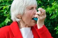 Portrait of grandmother have asthma, allergy attack outdoors. caucasian granny use aerosol, spray with drug, medicine