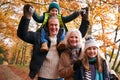 Portrait Of Grandparents With Grandchildren Enjoying Walk Along Autumn Woodland Path Together