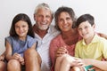 Portrait Of Grandparents With Grandchildren Sitting By Wall