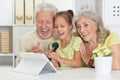Grandparents with her granddaughter singing karaoke with tablet Royalty Free Stock Photo