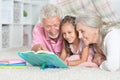 Portrait of grandparents reading book with little granddaughter Royalty Free Stock Photo