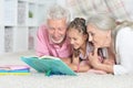 Portrait of grandparents reading book with little granddaughter Royalty Free Stock Photo