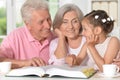 Portrait of grandparents reading book with little granddaughter Royalty Free Stock Photo