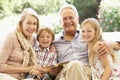 Portrait Of Grandparents Reading To Grandchildren On Sofa