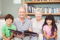 Portrait of grandparents showing album to grandchildren