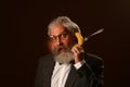 Portrait of a gray-haired elderly gentleman, with a shaggy mustache and beard, in a white shirt and gray jacket, wearing glasses Royalty Free Stock Photo