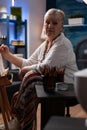 Portrait of gray haired older hobby artist studying shading light on still life using model vase Royalty Free Stock Photo