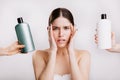 Portrait of green-eyed woman without makeup on isolated background. Girl decides which shampoo is better to use.