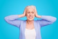 Portrait of grey haired old nice beautiful annoyed woman with palms on head. Isolated over violet purple background