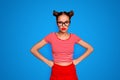 Portrait of grimacing offended young gorgeous woman model with with hands on waist and bun hairstyle isolated on red Royalty Free Stock Photo