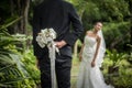 Portrait of a groom hiding a flowers bouquet behind his back to surprise