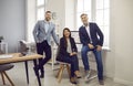 Group of business people of three looking at the camera and smiling at the workplace.