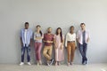 Portrait of a group of smiling multiracial people standing in a row on a light wall background. Royalty Free Stock Photo