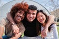 Portrait of a group of teenage students smiling and bonding at university campus. Three multiracial friends hugging and Royalty Free Stock Photo
