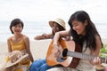 Portrait group of young asian woman palying guitar in sea beach