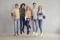 Portrait of a group of young cheerful girls and boys students jumping on a gray wall background. Royalty Free Stock Photo