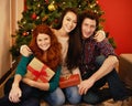 Sharing the love. Portrait of a group of young friends sitting by a Christmas tree holding their presents. Royalty Free Stock Photo