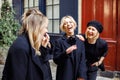 Portrait of group of young women standing on street near colored walls, conversing interacting sharing funny stores.