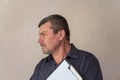 Portrait of a grown man holding a clipboard. A man with a short haircut and graying hair. White blank piece of paper clutched in Royalty Free Stock Photo