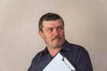 Portrait of a grown man holding a clipboard. A man with a short haircut and graying hair. White blank piece of paper clutched in Royalty Free Stock Photo