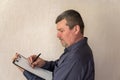 Portrait of a grown man taking notes into a clipboard. Man with short haircut and graying hair. White blank piece of paper Royalty Free Stock Photo