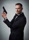 Portrait, gun and man in studio with weapon for power, crime or secret mission on grey background. Face, handgun and
