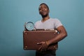 Portrait of guy holding retro suitcase and clock in front of camera Royalty Free Stock Photo