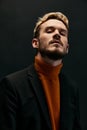 portrait of a guy in an orange sweater and coat on a dark background close-up cropped view of a blond man Royalty Free Stock Photo