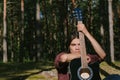 Portrait of a Guy sitting in the woods with a guitar. Against the background of the forest camp