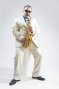 Portrait of Hadnsome Male Saxophone Player Performing In Studio Environment. Wearing White Suit and Sunglasses