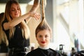 Hairdresser holding long lock of hair and going to cut length with scissors