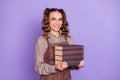 Portrait of half turned adorable person hands hold stack of book beaming smile isolated on purple color background Royalty Free Stock Photo