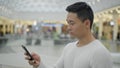 Portrait of hamdsome asian man scrolling phone on big mall background