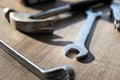 A portrait of  a hammer, an open end and a box end wrench lying on a wooden table. The tools are being used to perform a Royalty Free Stock Photo