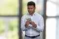 Portrait of handcuffed Indian man holding money. Blur interior background.