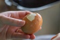 A portrait of the hands of a person peeling the shell of a hard boiled egg, making it ready to eat for breakfast, lunch or maybe