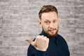 Portrait of handsome adult man on brick wall background. Caucasian man with beard showing finger aside Royalty Free Stock Photo