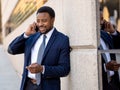 Portrait of handsome african american businessman walking in the city talking on mobile phone Royalty Free Stock Photo