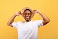 Portrait of handsome African American man in casual clothes, straw hat and sunglasses on yelow studio background Royalty Free Stock Photo