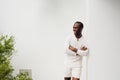 Handsome african american man smiling with arms crossed and leaning against white wall Royalty Free Stock Photo