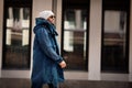 Portrait of handsome African American man walking in city, wearing stylish outfit parka coat, knitted hat and sunglasses Royalty Free Stock Photo