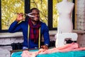 Portrait of a handsome african man smiling seamstress with sewing machine.Afrio American man stylish designer working in