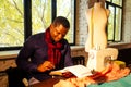 Portrait of a handsome african man smiling seamstress with sewing machine.Afrio American man stylish designer working in