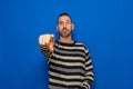 Portrait of handsome angry man pointing index finger at you on isolated blue background, looking at camera. Upset strict Royalty Free Stock Photo