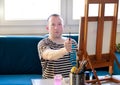 Portrait of handsome artist measuring proportions with paintbrush. Male artist painter working in workshop with canvas.