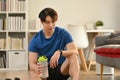 Portrait of a handsome asian man holding a bottle of water, resting after home workout Royalty Free Stock Photo